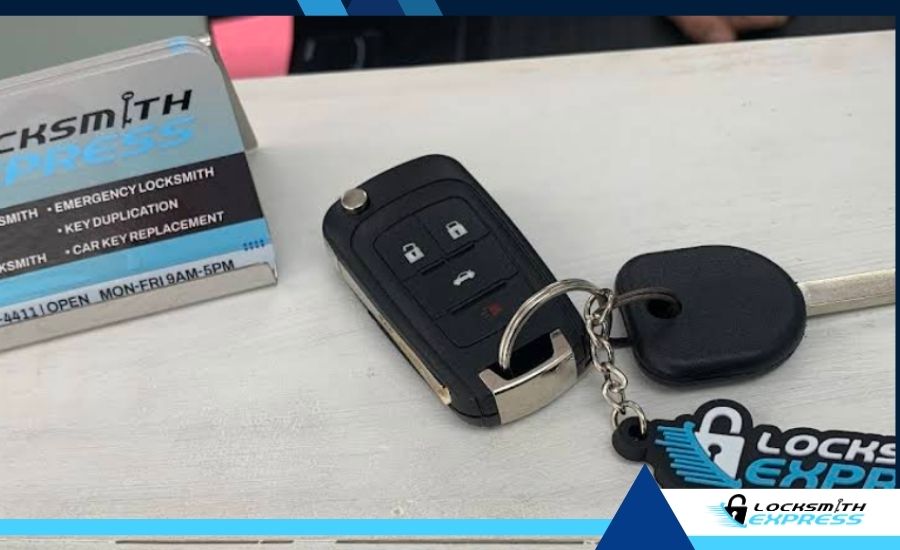 A car key fob and standard car key on a countertop next to a Locksmith Express business card holder and keychain.
